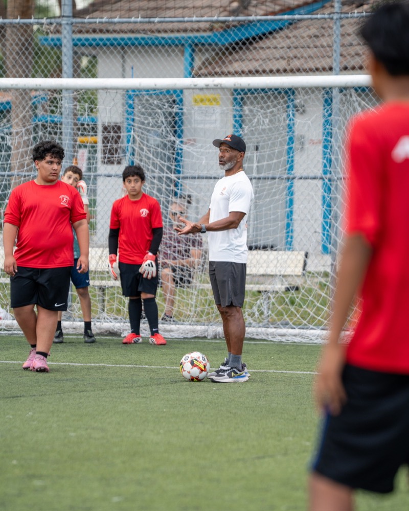 Entrenador explicando un ejercicio a los jugadores frente al arco
